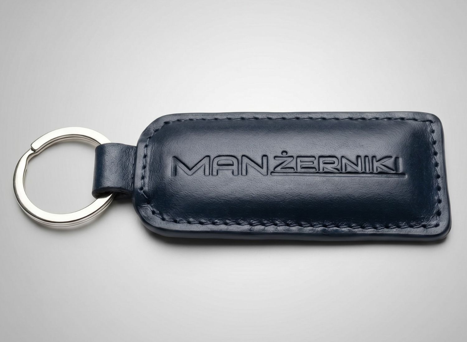 Granatowy wysokiej jakości skórzany brelok do kluczy z tłoczonym logo. Eleganckie upominki biznesowe dla dealerów samochodowych.