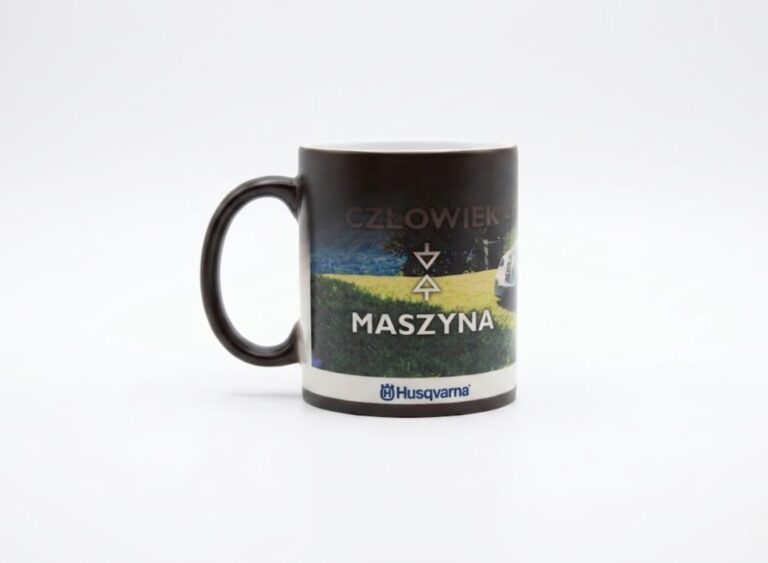 Kubek reklamowy z pełnokolorowym nadrukiem krajobrazu i hasłem człowiek maszyna. Trwała sublimacja z logo dla firm z branży przemysłowej.