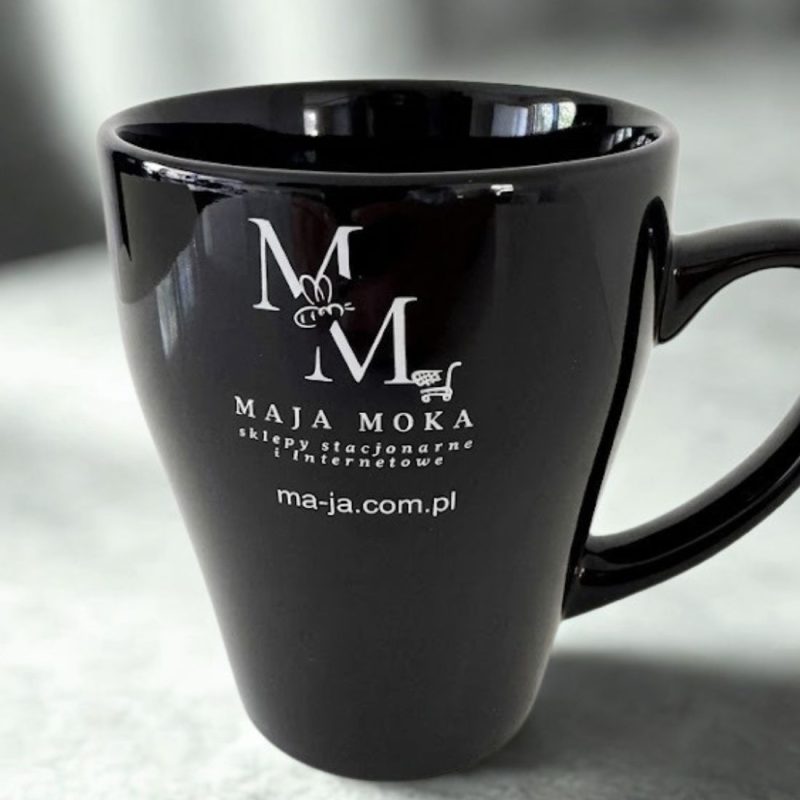 Czarny, lśniący kubek ceramiczny z białym, kontrastowym nadrukiem logo MAJA MOKA. Eleganckie upominki dla klientów.