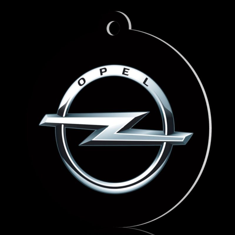 Oryginalna zawieszka zapachowa - zapach samochodowy z wyeksponowanym srebrnym logo marki Opel na czarnym tle.